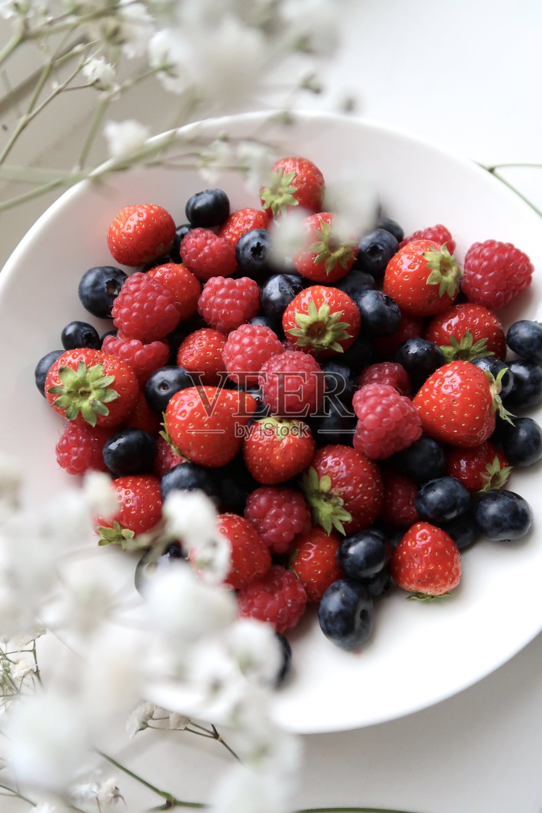 白碗浆果混合和白宝宝呼吸花照片摄影图片