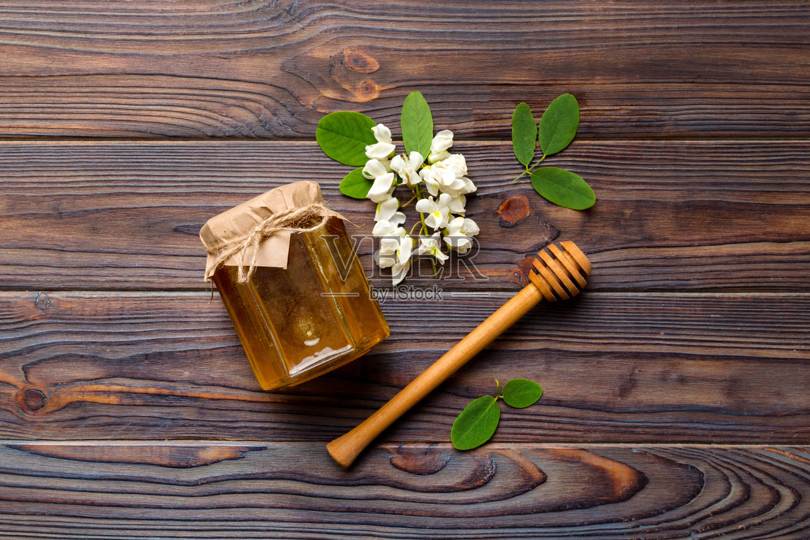 装有相思花和叶子的蜜罐。新鲜蜂蜜顶视图平躺照片摄影图片