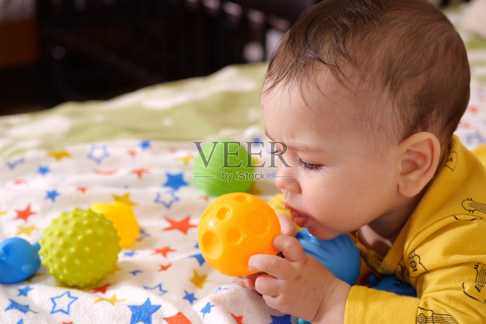 可爱可爱的新生儿在玩五颜六色的摇铃玩具。有牙齿的婴儿。六个月大的可爱的婴儿肖像在白色与牙齿玩具照片摄影图片