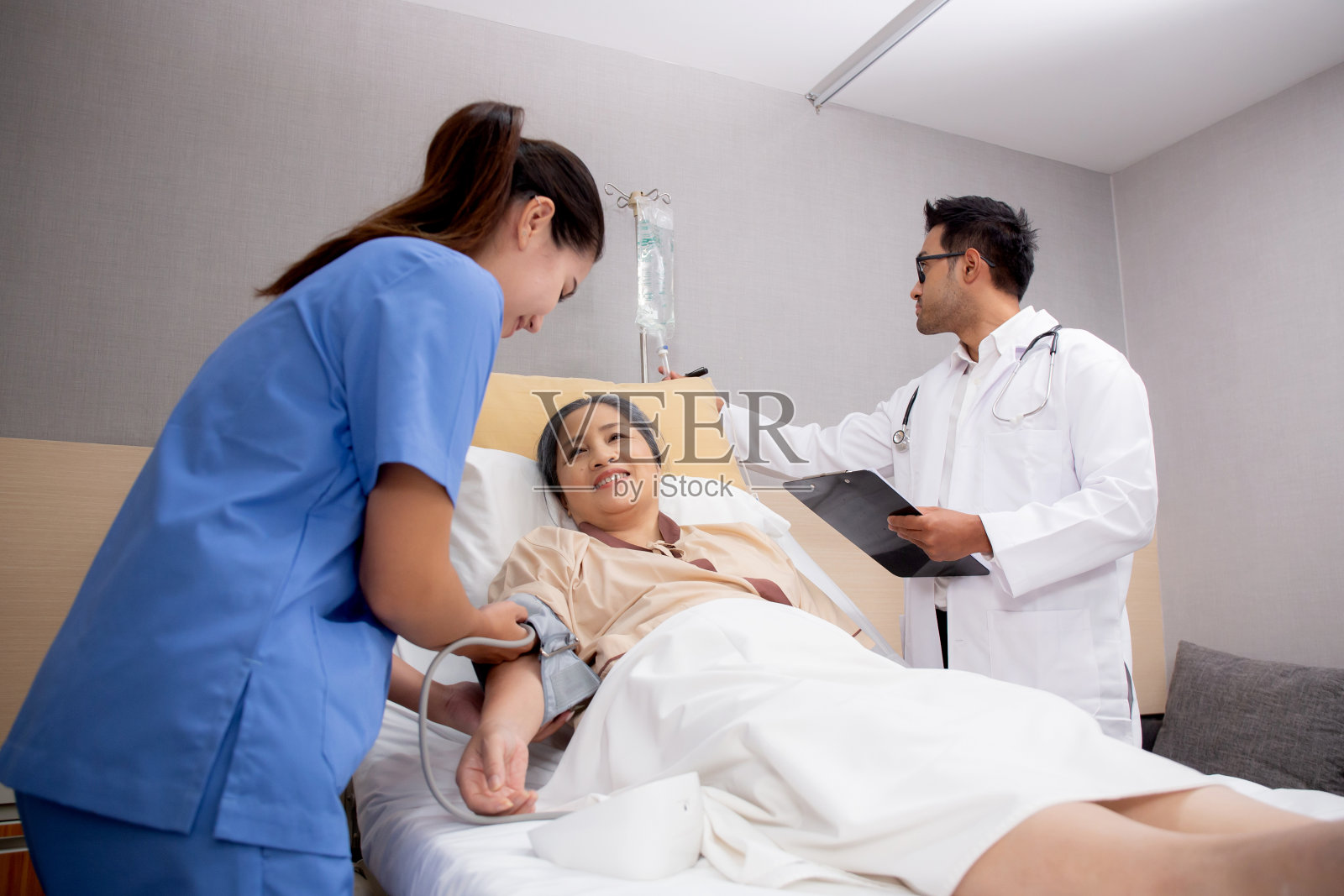 医生在医院病房检查和诊断病人，护士测量血压，医生在诊所诊断病人的疾病和护理，医疗和保险的概念。照片摄影图片