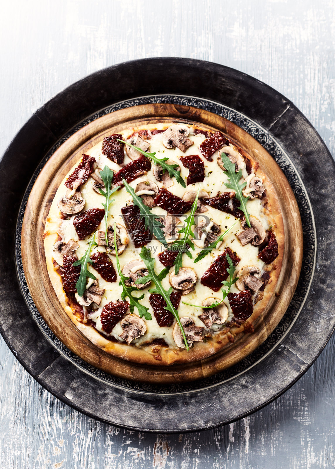 披萨配马苏里拉奶酪，腌番茄和新鲜火箭。明亮的木制背景。前视图。照片摄影图片