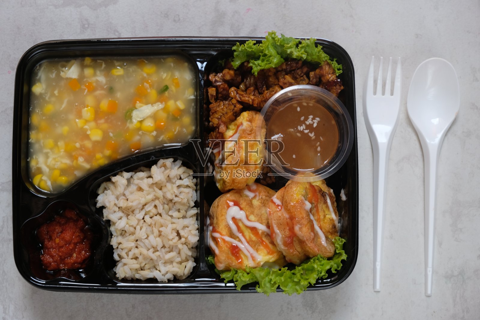 健康食品便当有糙米，煎蛋卷，蔬菜玉米汤，豆豉和水果果冻。为节食减肥计划。塑料容器里的健康午餐菜单。餐饮菜单饮食。照片摄影图片