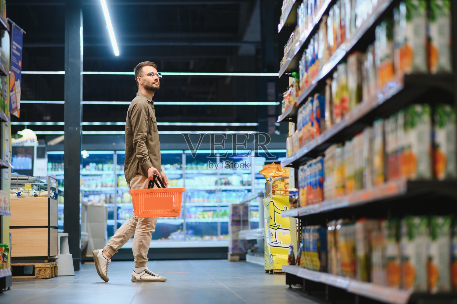 一个面带微笑的帅哥在超市购物，从货架上挑选食品照片摄影图片