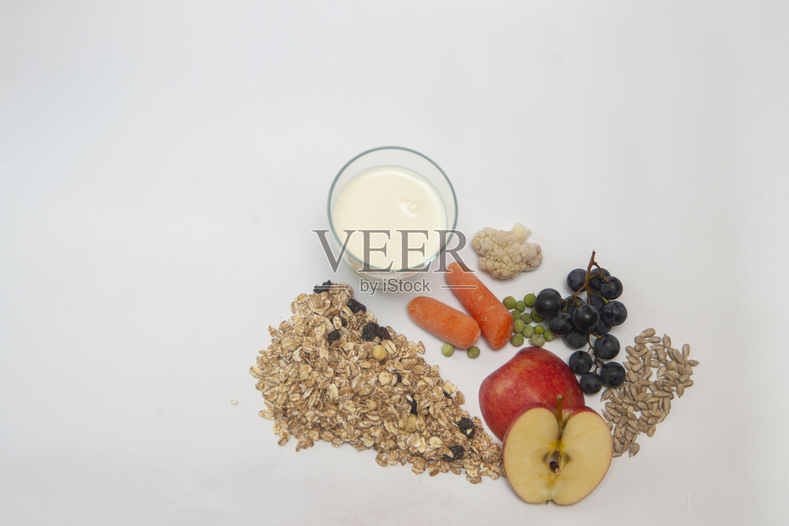 一杯牛奶，水果(苹果，葡萄)和蔬菜(胡萝卜，豌豆)，葵花籽，格兰诺拉麦片，什锦麦片照片摄影图片