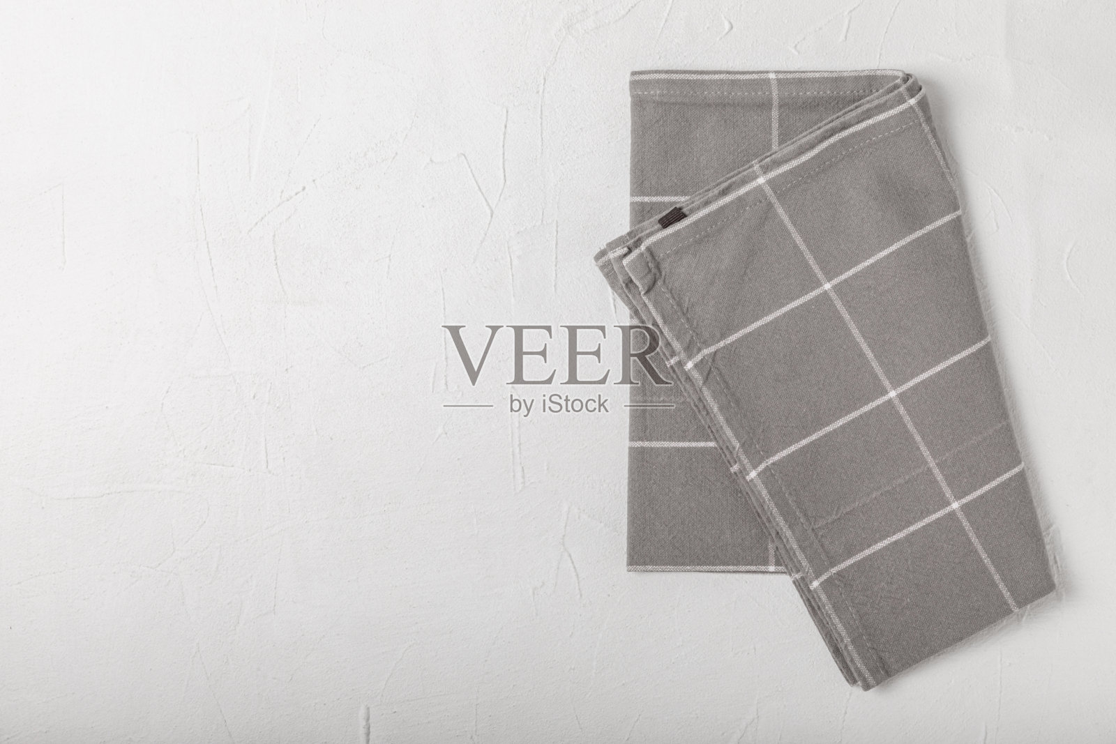 新的朴素图案厨房毛巾折叠在有纹理的桌子上。厨房用具。厨房毛巾或餐巾纸。文本的复制空间。放文字的地方。桌布。照片摄影图片