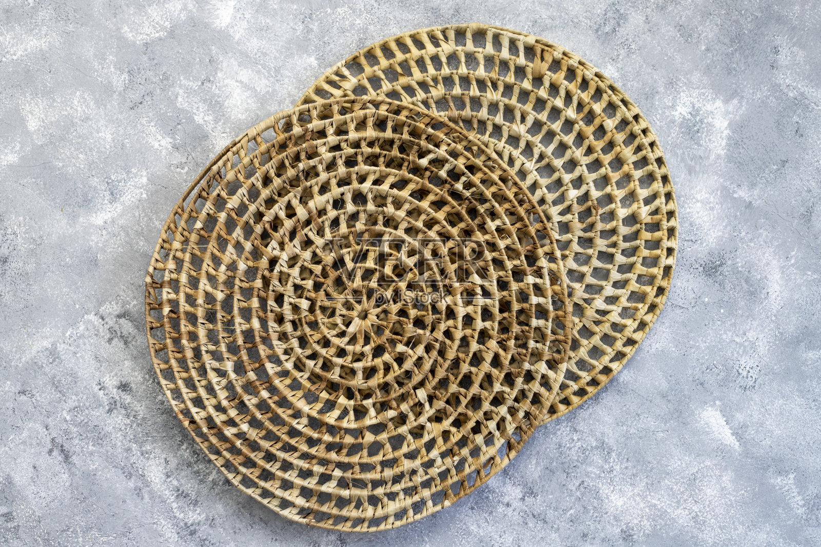 藤编圆形餐垫放置在木制背景上。从上面看照片摄影图片