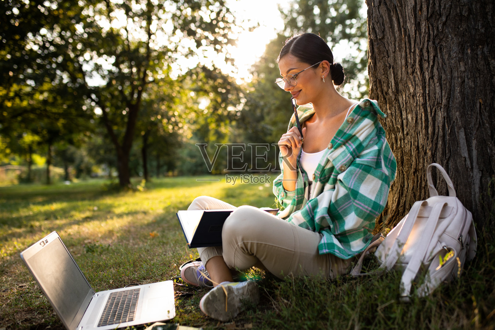 一个漂亮的女人坐在公园的草地上干活照片摄影图片