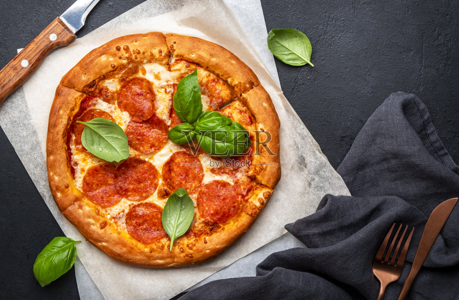 辣香肠披萨配意大利腊肠，奶酪，辣味番茄酱和绿色罗勒叶，即食，黑色背景，俯视图照片摄影图片