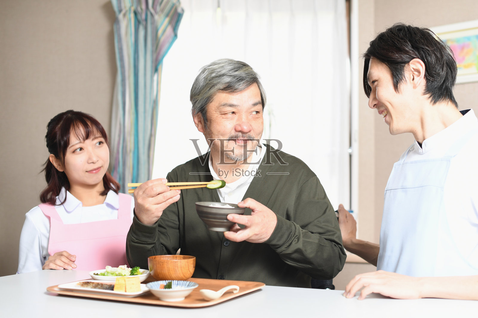 正在吃饭的亚洲老人和穿着围裙的男保姆和女保姆照片摄影图片