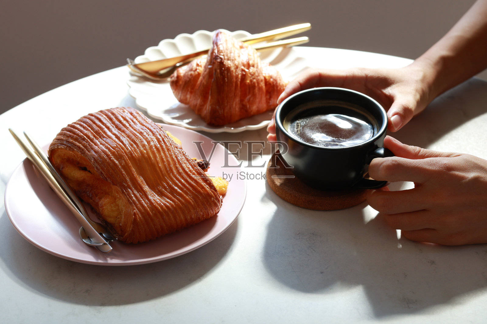 一个年轻的女人享受她的早餐，法国糕点和一杯热咖啡的早晨在咖啡馆照片摄影图片