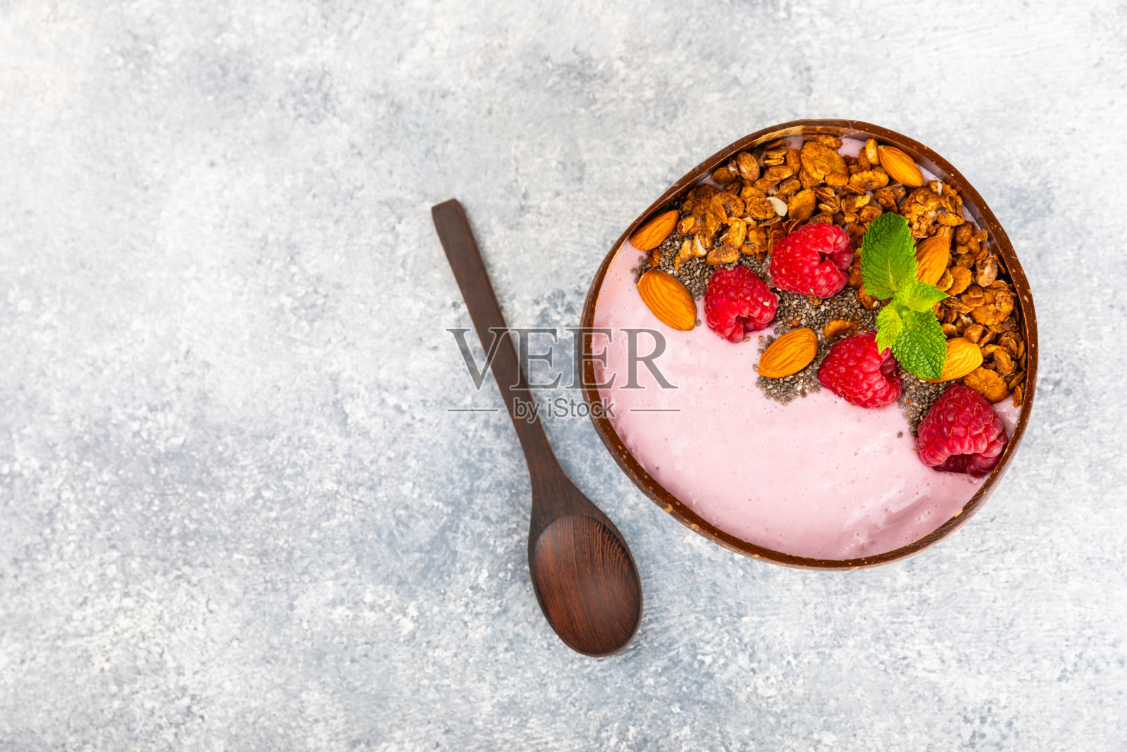 格兰诺拉麦片碗，酸奶和新鲜的杏仁，蓝莓，覆盆子，桃子，猕猴桃，草莓和香蕉在纹理厨房的桌子上。巴西莓和螺旋藻碗。健康早餐概念。副本的空间。照片摄影图片