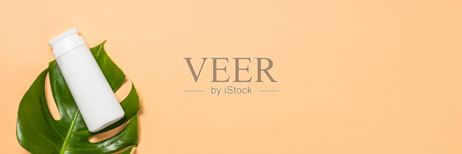 化妆品瓶和绿叶在米色背景。照片摄影图片