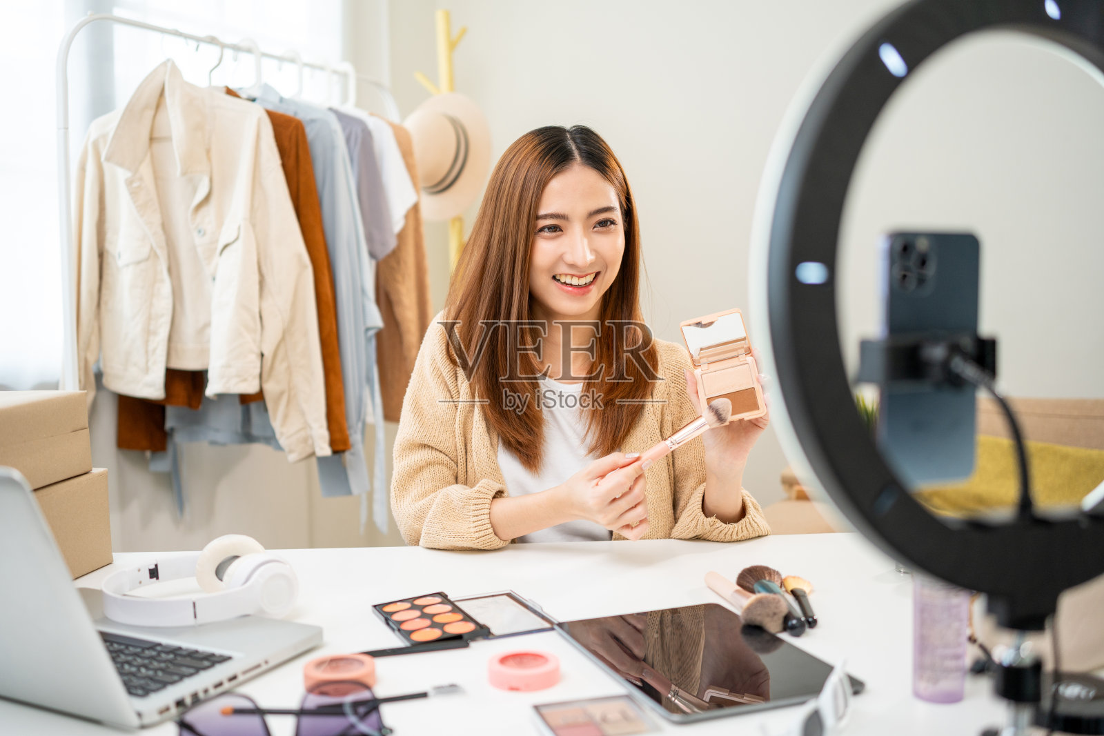 年轻美丽的亚洲女性视频博主直播化妆化妆教程内容用刷看手机。有影响力的人在社交媒体上分享各种化妆品记录评论视频照片摄影图片