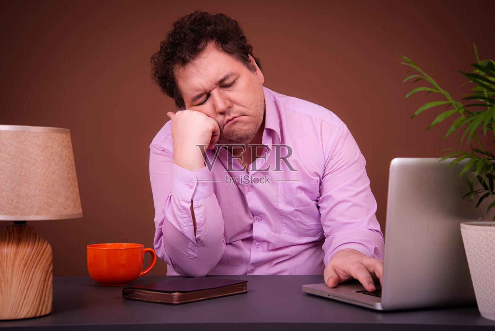 滑稽的胖子拿着笔记本电脑在桌子旁摆姿势。清晨在线辛苦工作照片摄影图片