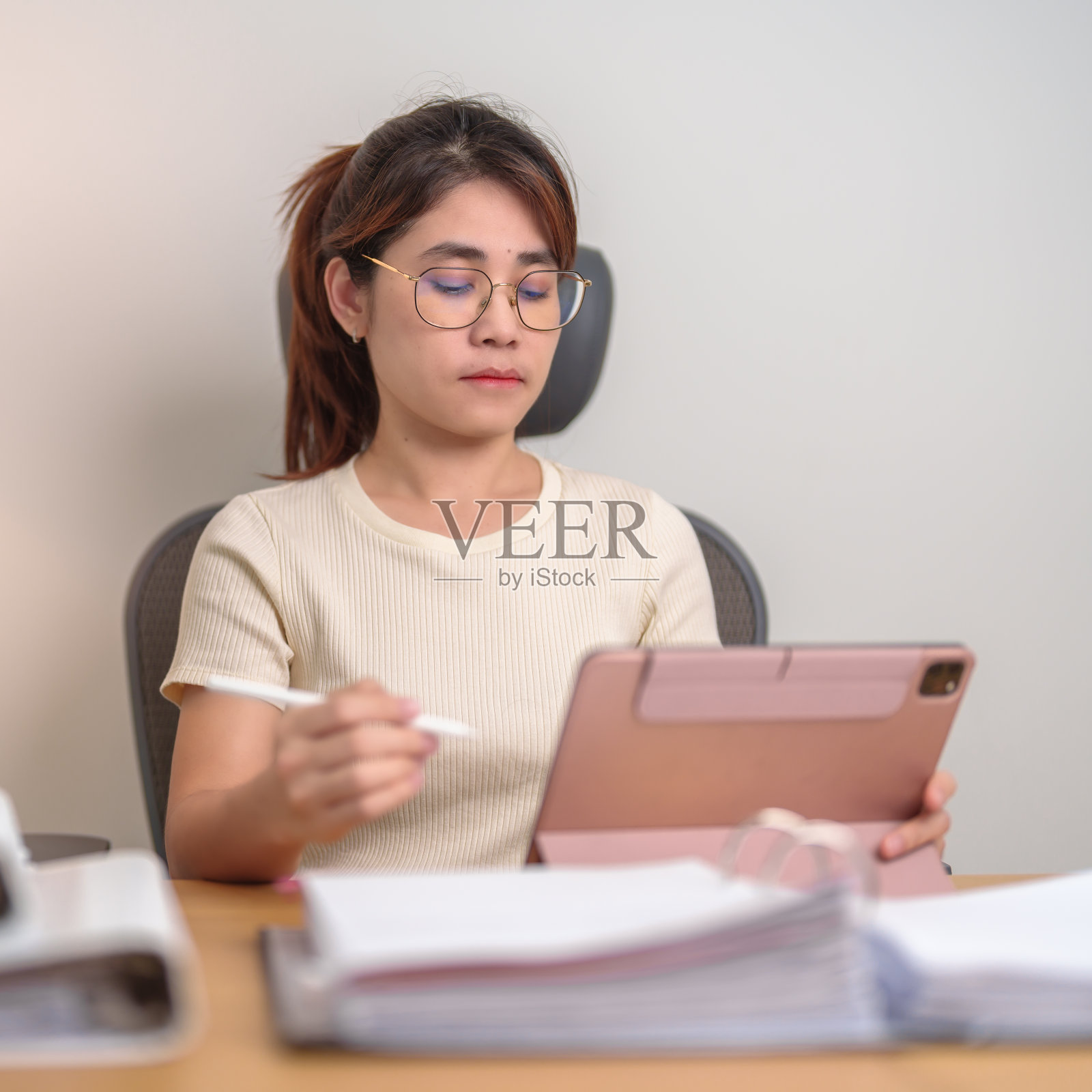 年轻聪明的女人通过平板电脑进行视频会议。在家里或办公室深夜与成堆的文件进行在线会议。电话会议和技术概念照片摄影图片