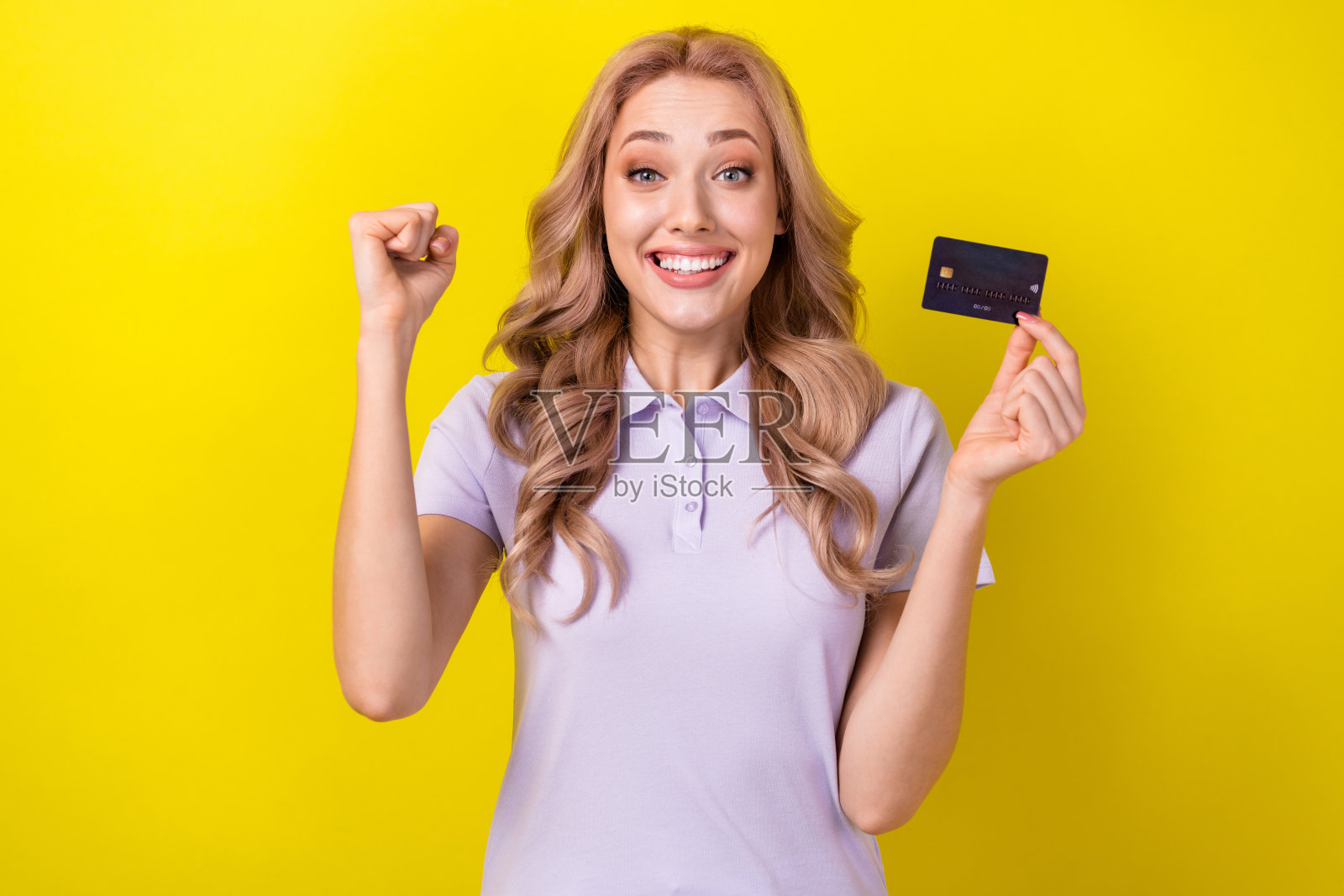 喜出望外的人手持借记卡举拳成就的照片孤立在黄色背景上照片摄影图片