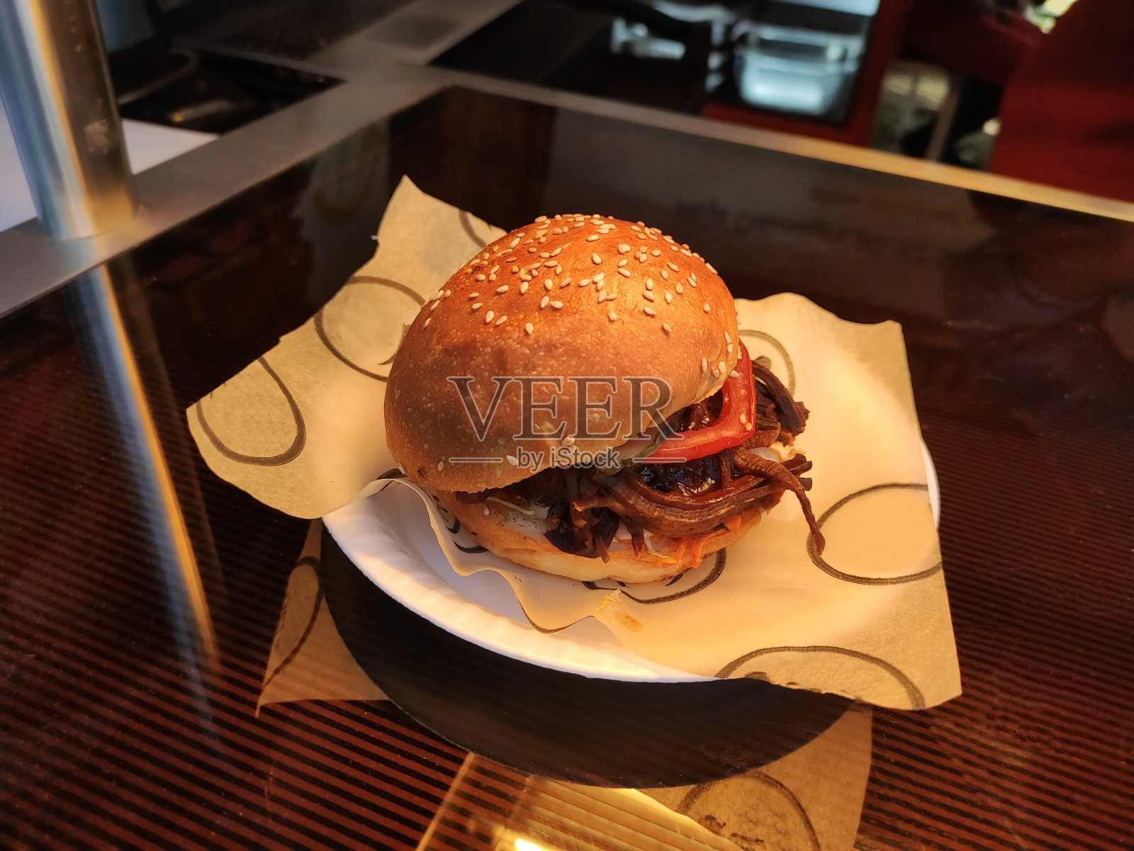 美味的汉堡配上肉和蔬菜，洒上芝麻，放在咖啡馆橱窗里的盘子里照片摄影图片