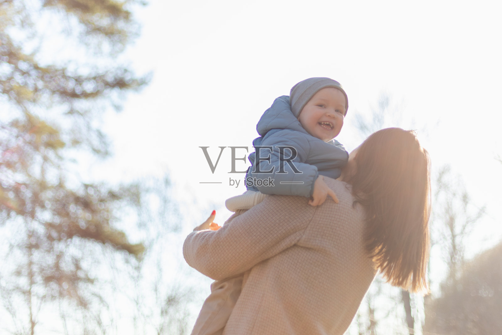 幸福的家庭户外。母亲在户外拥抱她的孩子。妈妈在空中举起蹒跚学步的孩子儿子。女人和小男孩在公园散步休息。妈妈带着爱和关怀拥抱着婴儿。照片摄影图片