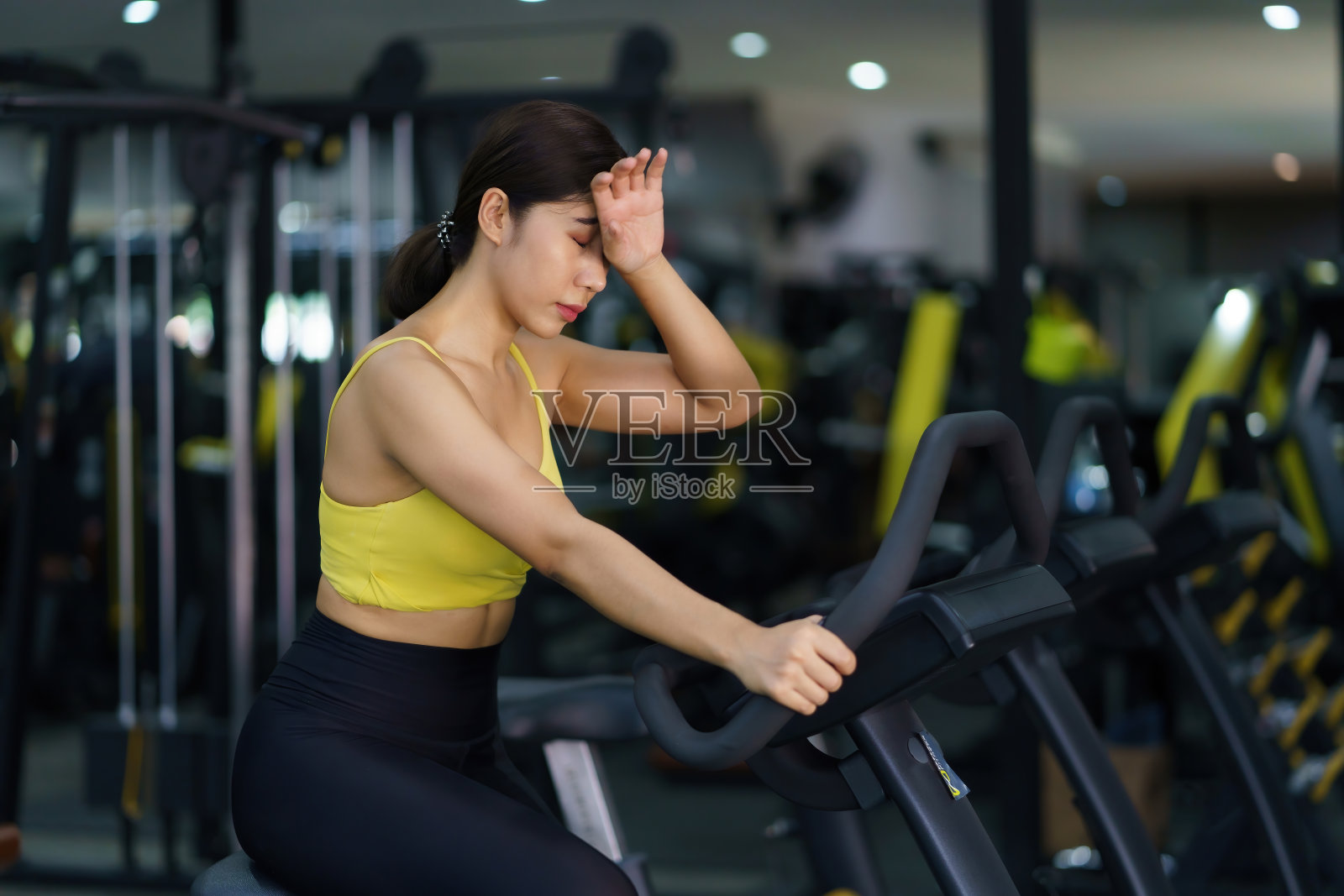 美丽的亚洲女人在健身房骑自行车锻炼，以获得强壮和美丽的肌肉。照片摄影图片