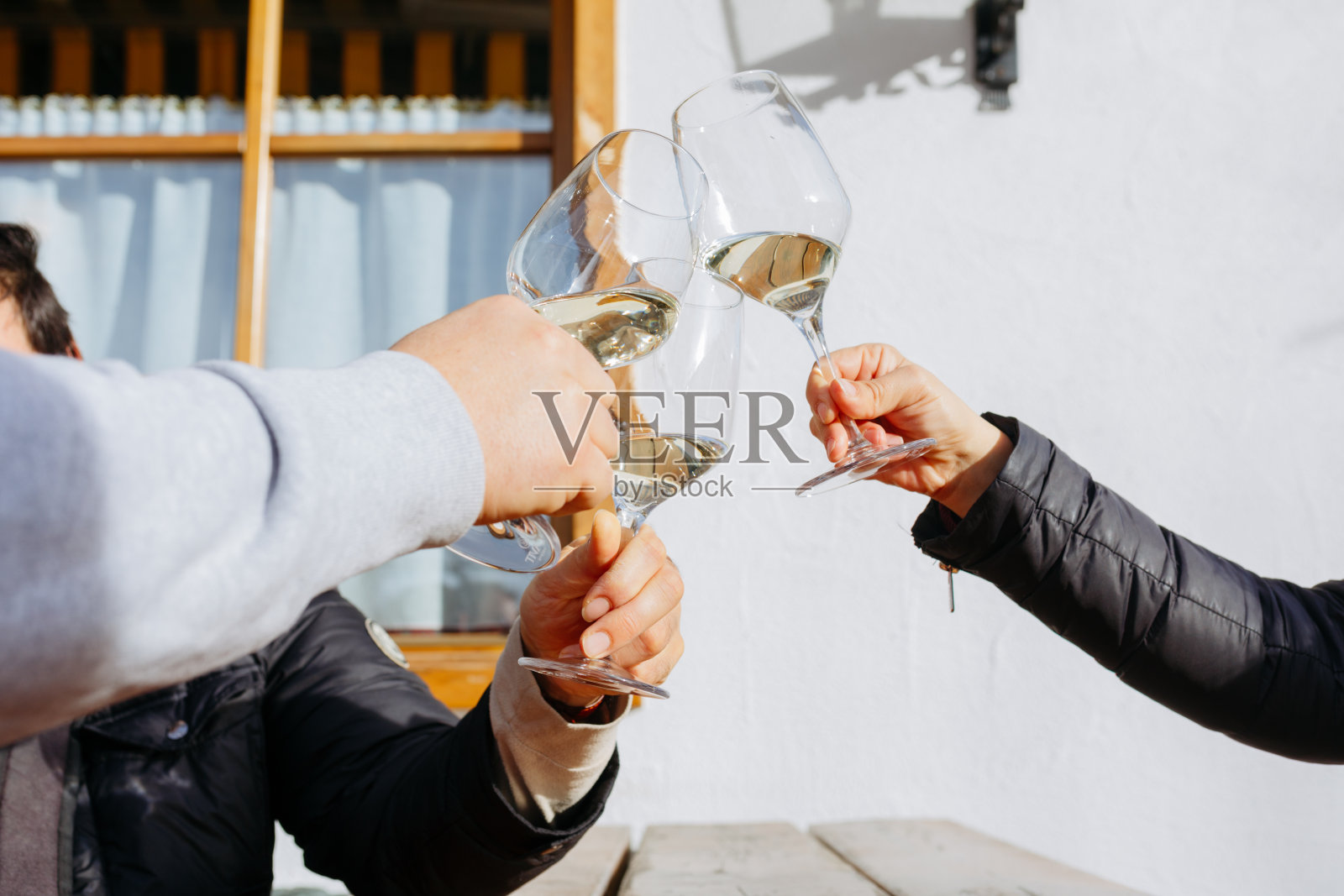 低角度的三个人的手拿着酒杯的起泡酒对着白色的墙照片摄影图片