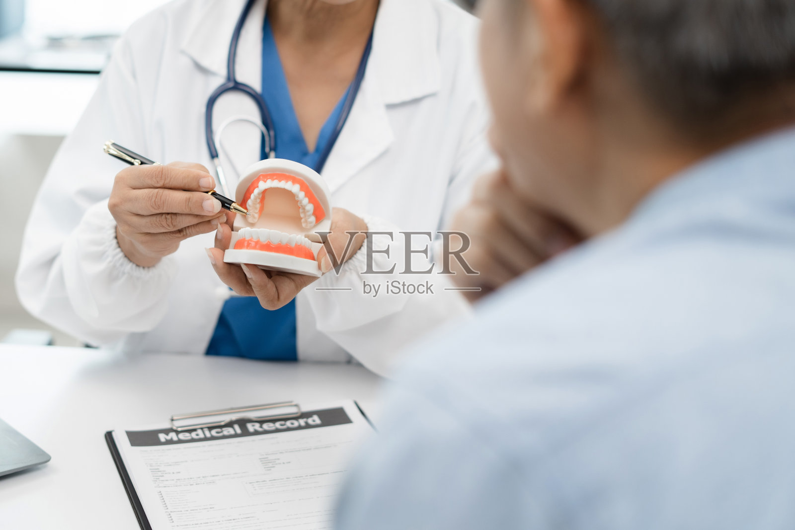 牙医在办公室工作的牙齿模型，早上在办公桌牙医和推荐病人在工作场所的概念。照片摄影图片