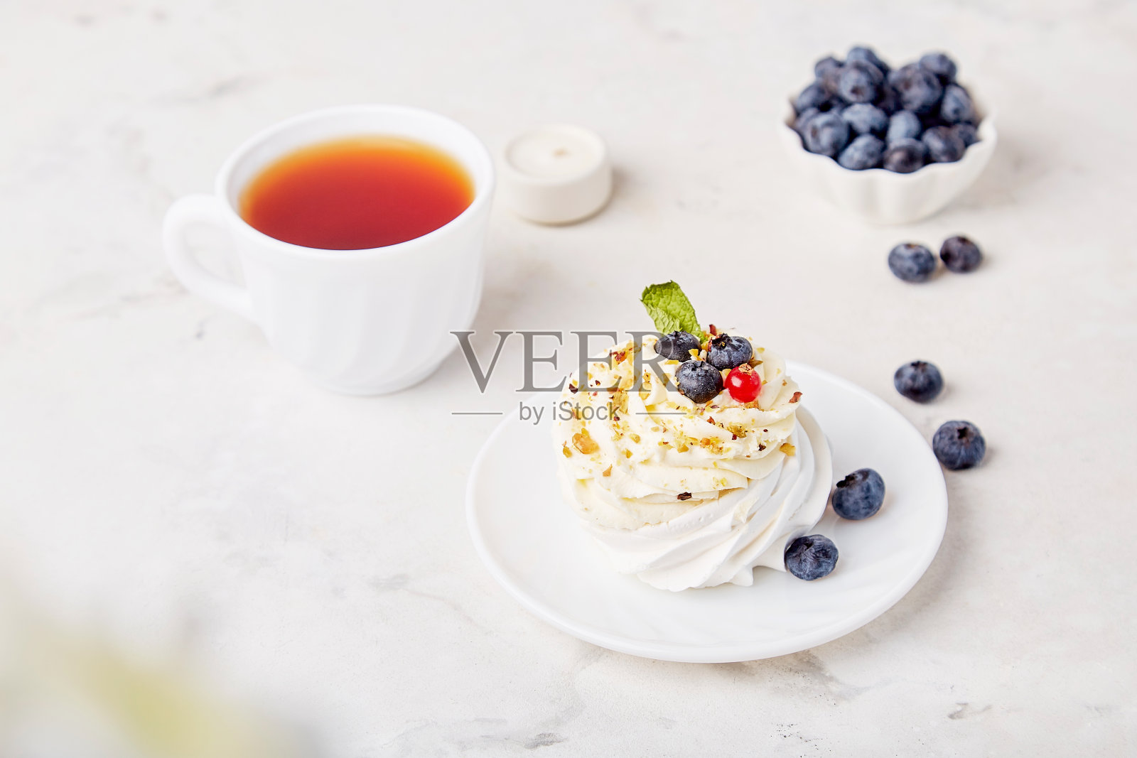 传统的巴甫洛娃甜点配上茶杯和蓝莓。秋天的茶点时间，背景的气息。Hygge美学照片摄影图片