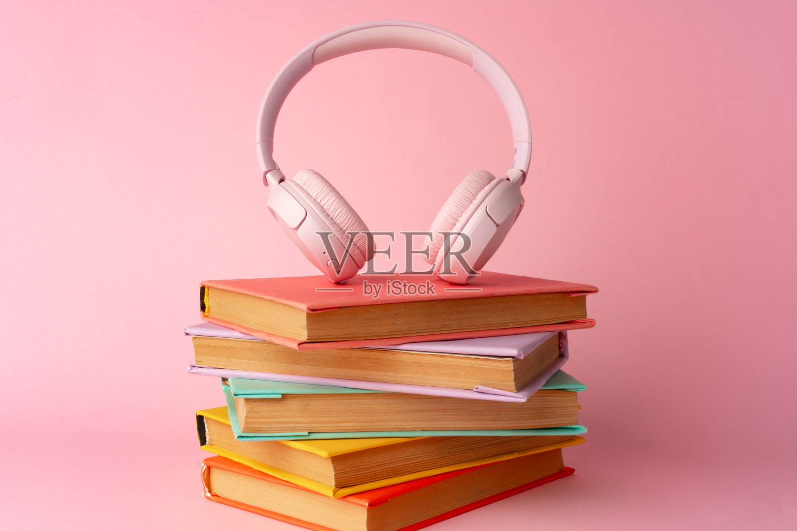 粉色耳机配上蓝色背景的书照片摄影图片