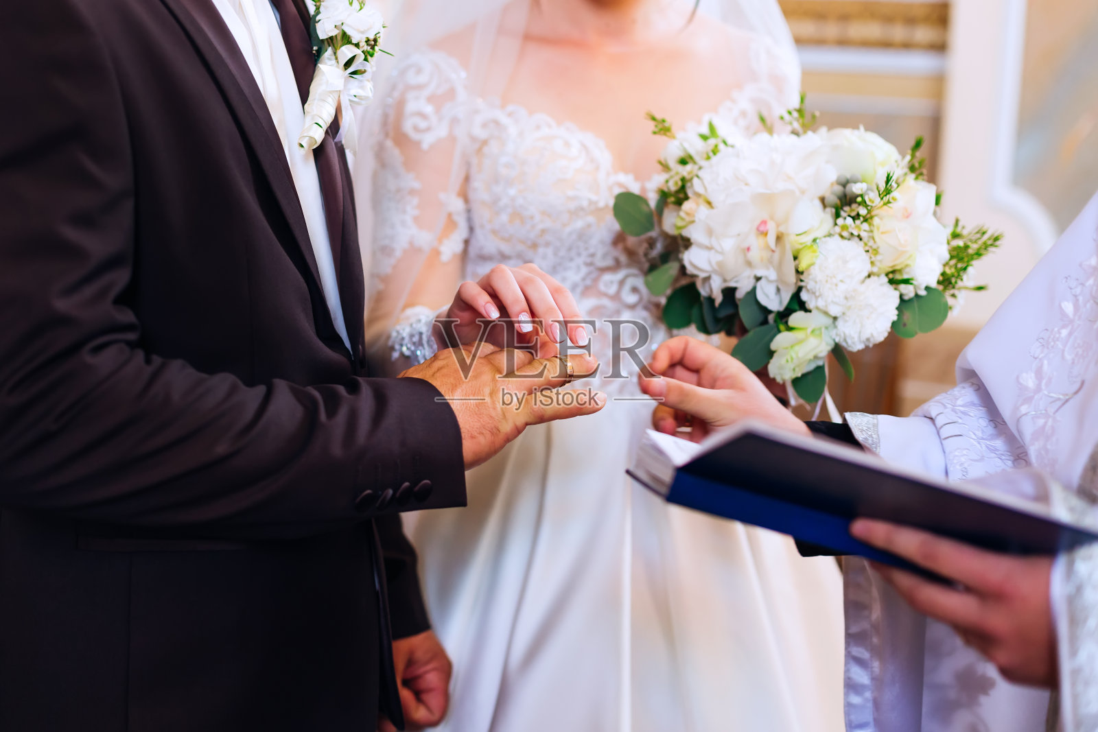 新娘和新郎肩并肩站在牧师面前交换结婚戒指照片摄影图片