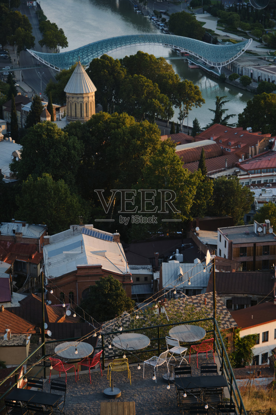 格鲁吉亚首都第比利斯的晨景。屋顶的房屋，教堂和库拉河与现代人行天桥。空街咖啡馆俯视图。照片摄影图片