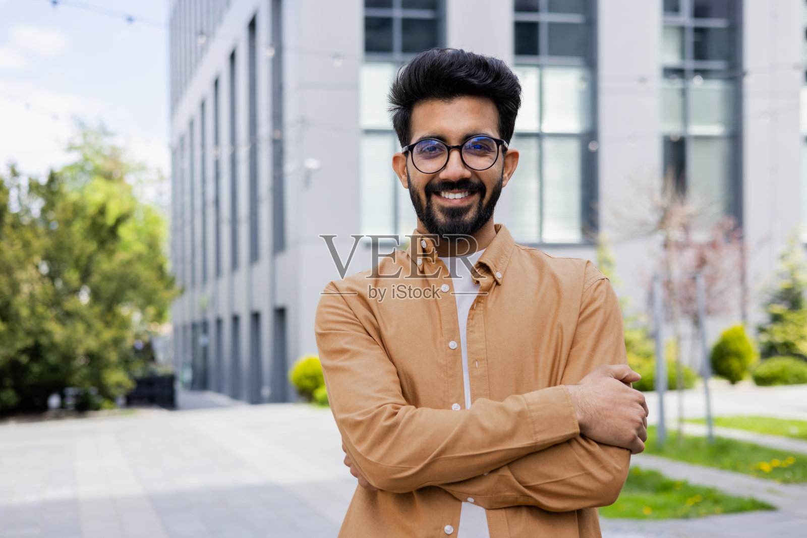 年轻拉丁裔男学生戴眼镜，双臂交叉照片摄影图片