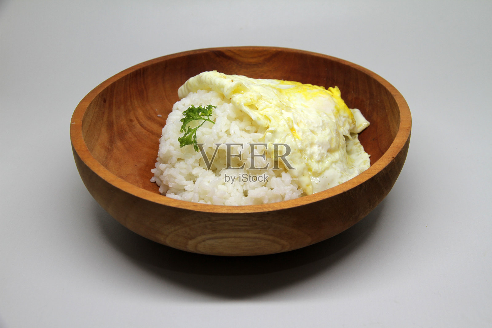 白色背景的木碗里装着白米饭和煎蛋照片摄影图片