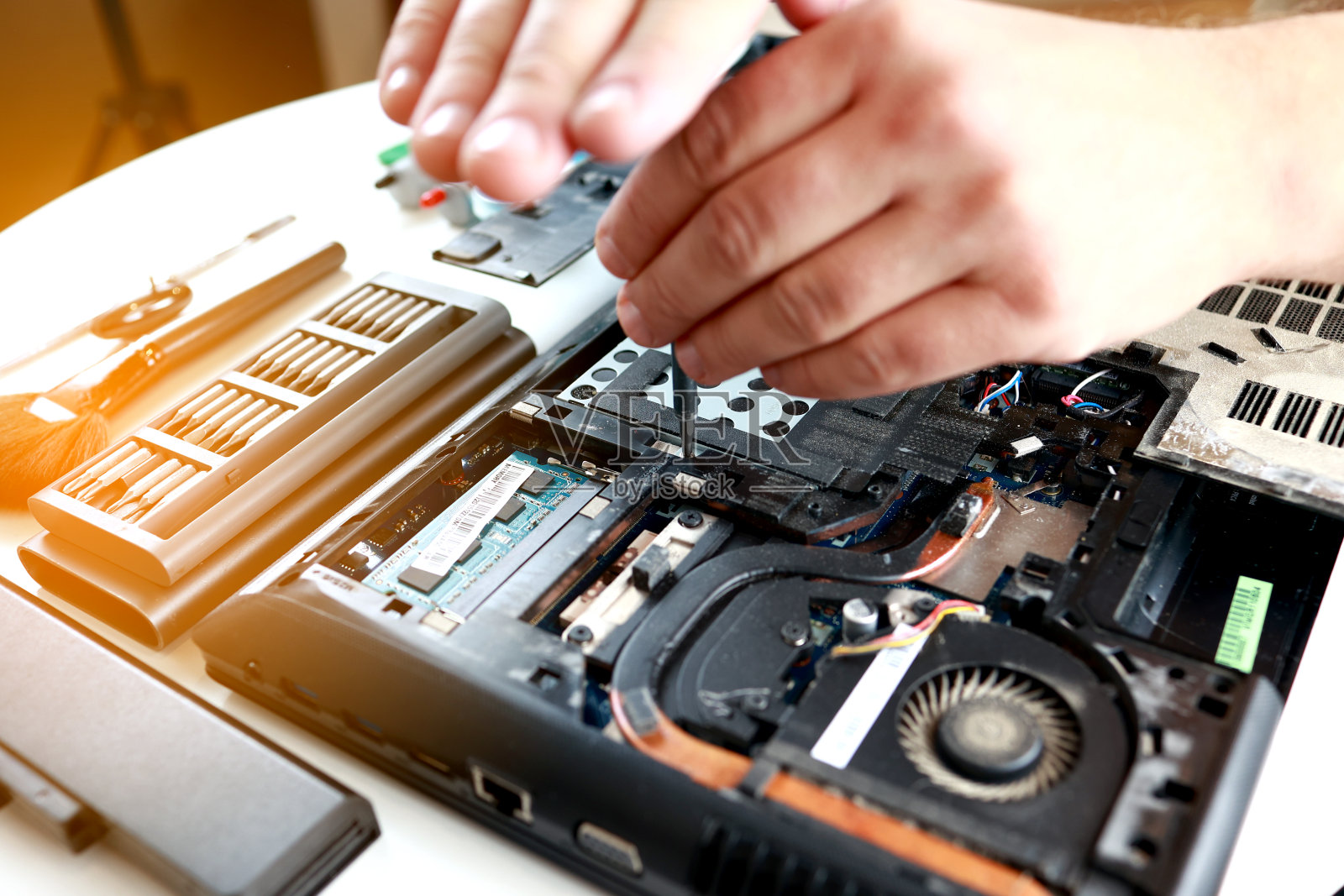 修理工用螺丝刀固定拆卸的笔记本电脑部件。技术支持和解决设备问题。维修、清洁、保养电脑。修理店。硬件maintenanc照片摄影图片