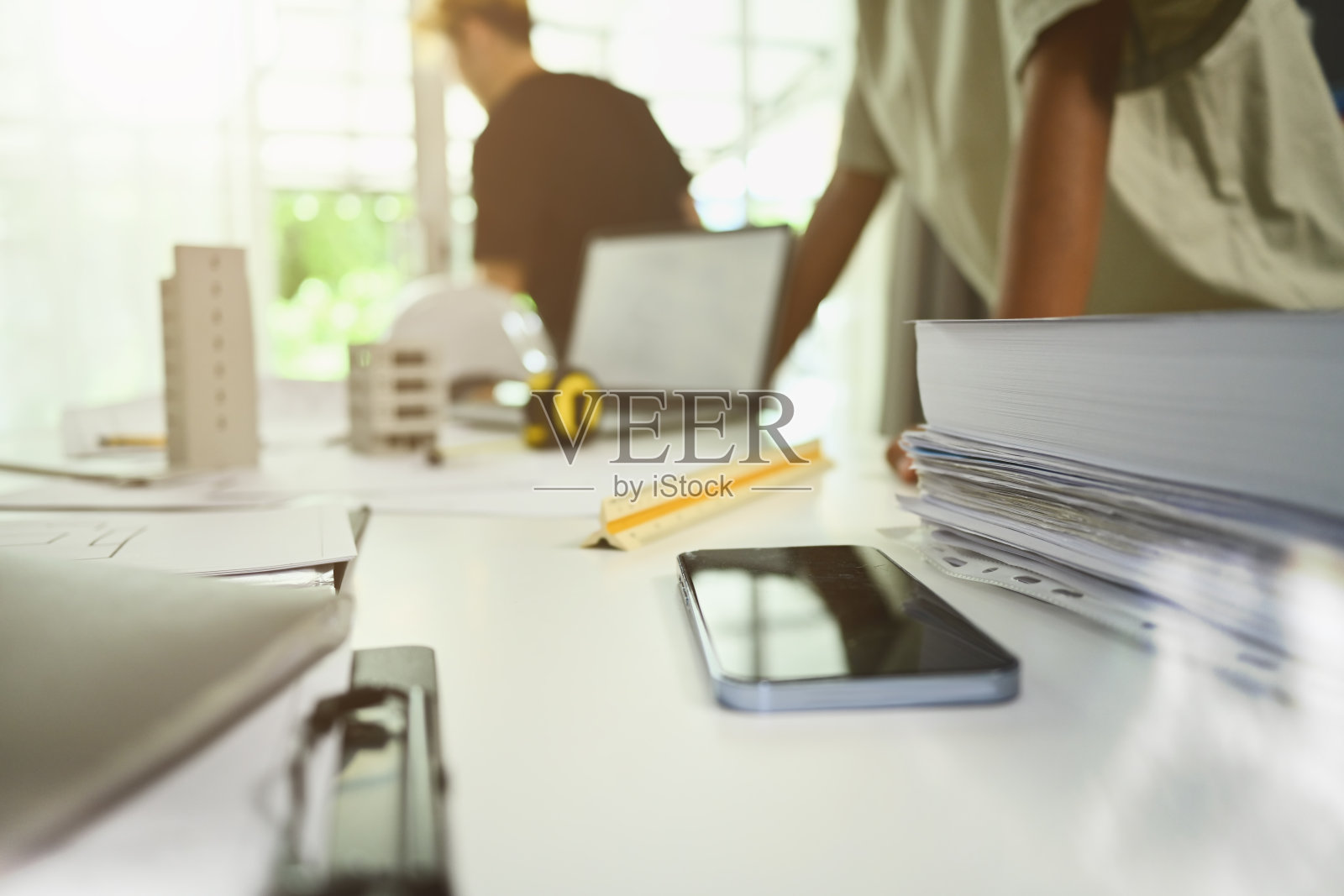 在现代办公室里，建筑师们在女桌子上放着数码平板电脑、安全帽和蓝图照片摄影图片