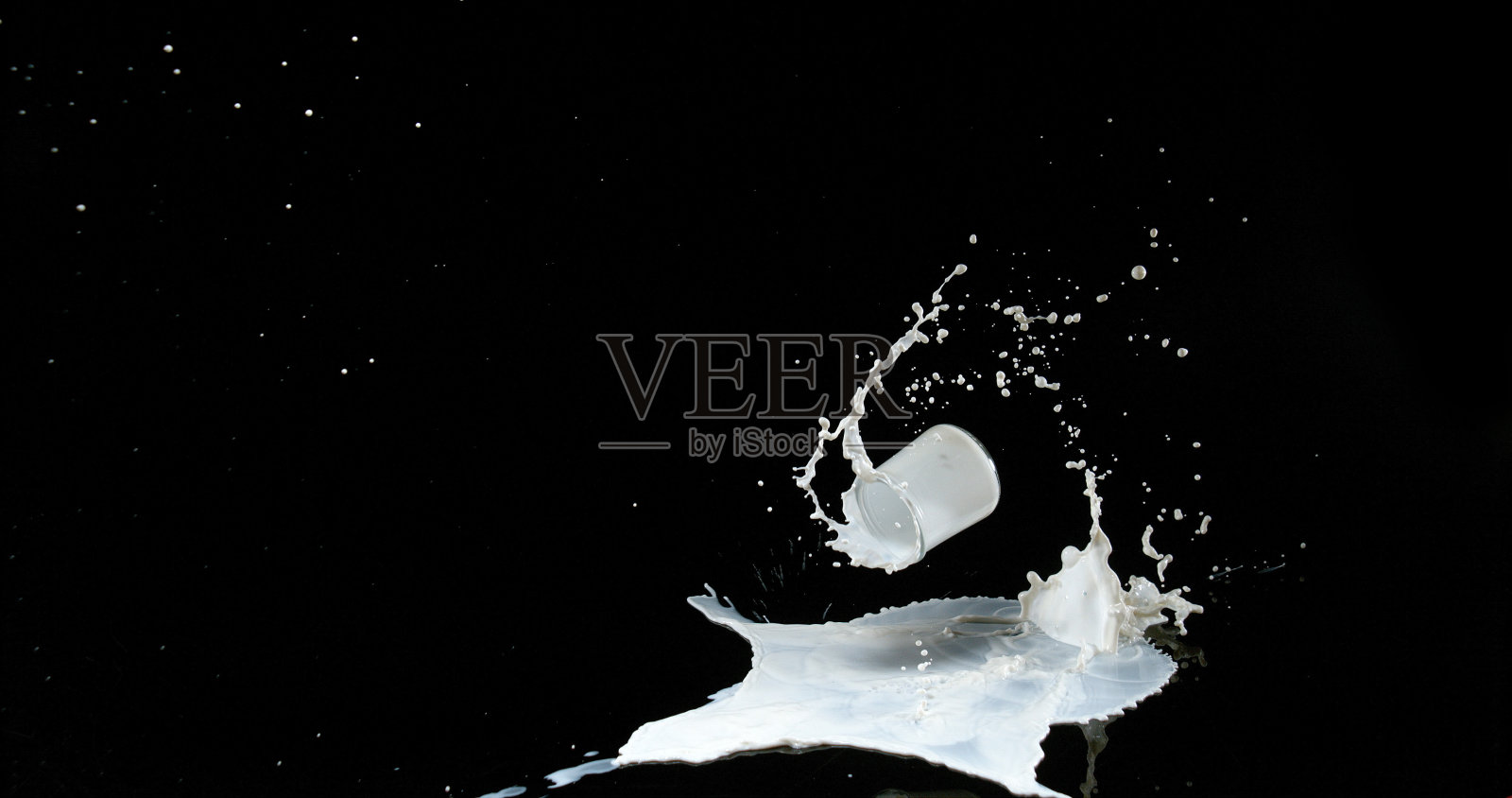 一杯牛奶在黑色背景上跳跃和飞溅照片摄影图片