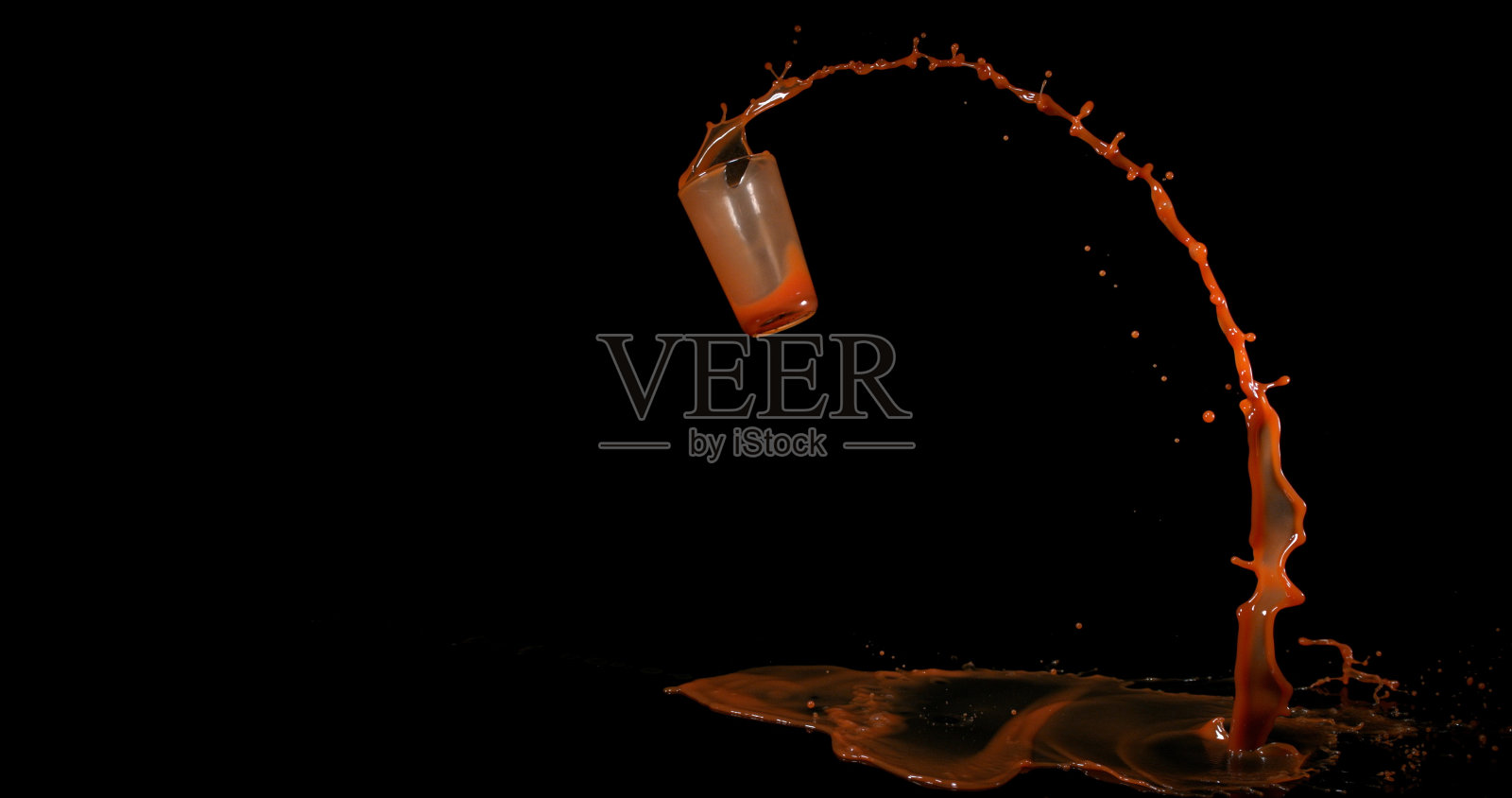 一杯番茄汁弹跳和飞溅在黑色的背景照片摄影图片