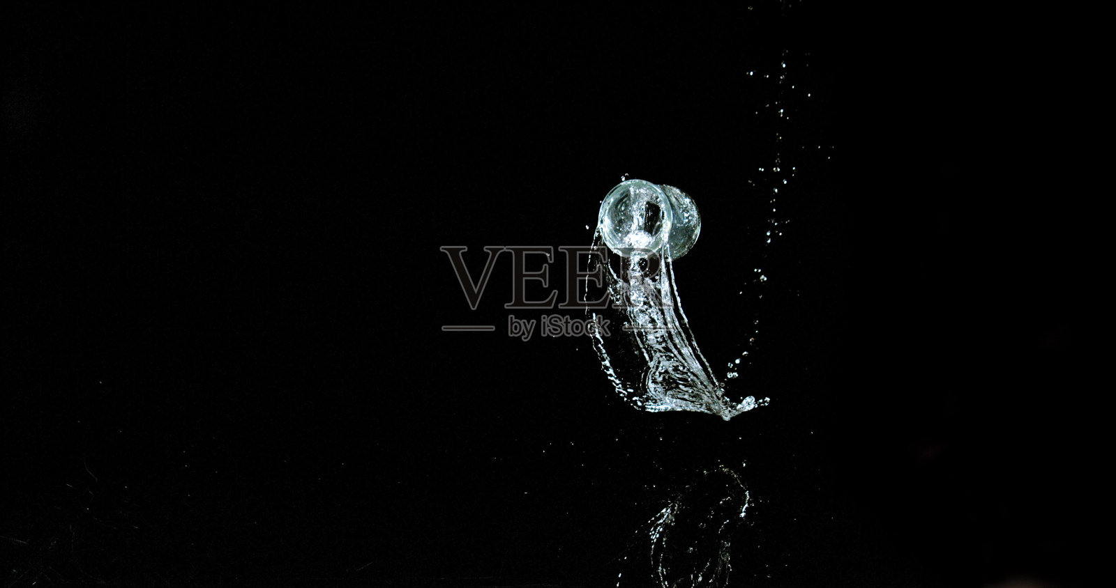 一杯水弹跳和飞溅在黑色背景照片摄影图片