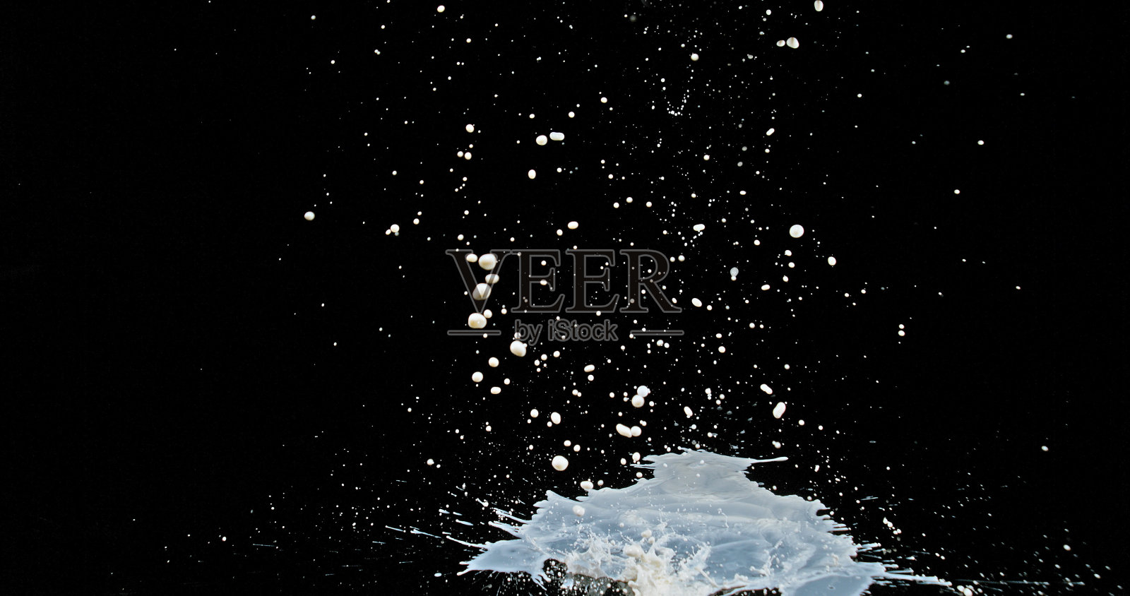 牛奶弹跳和溅在黑色的背景照片摄影图片