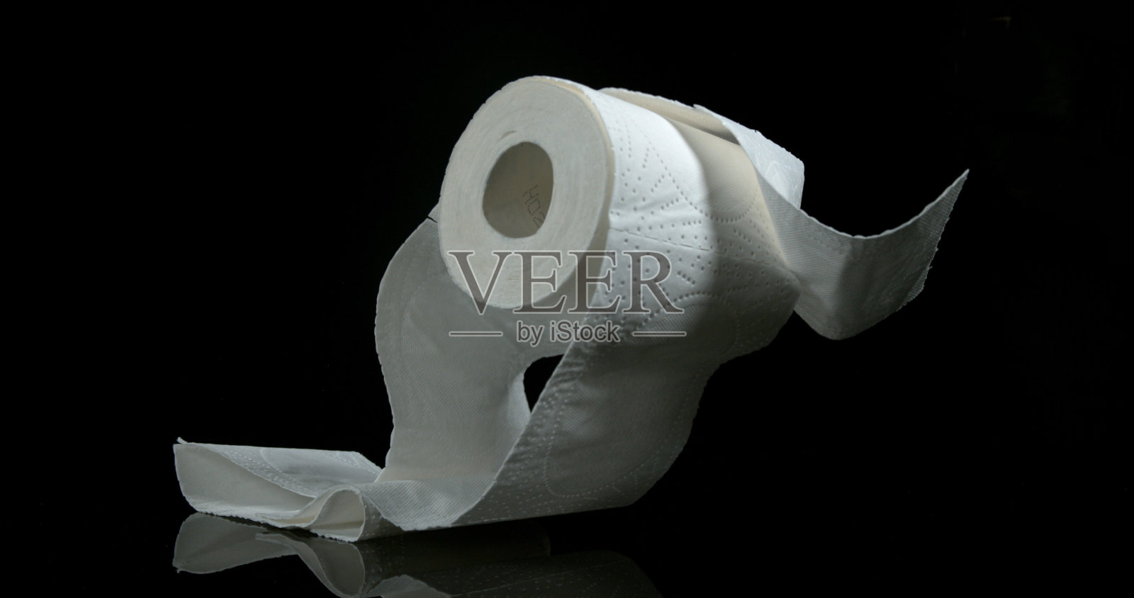 一卷厕纸落在黑色背景上照片摄影图片