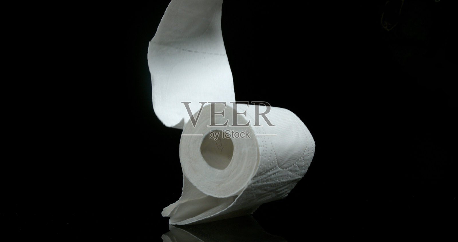一卷厕纸落在黑色背景上照片摄影图片