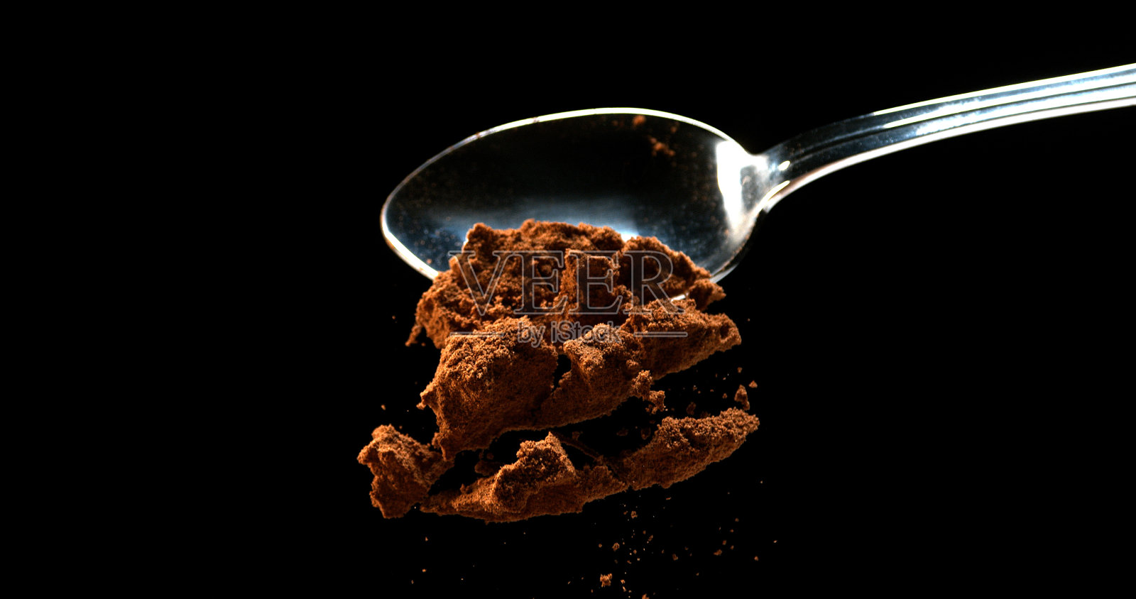 肉豆蔻，肉豆蔻，粉末从勺子落在黑色背景照片摄影图片