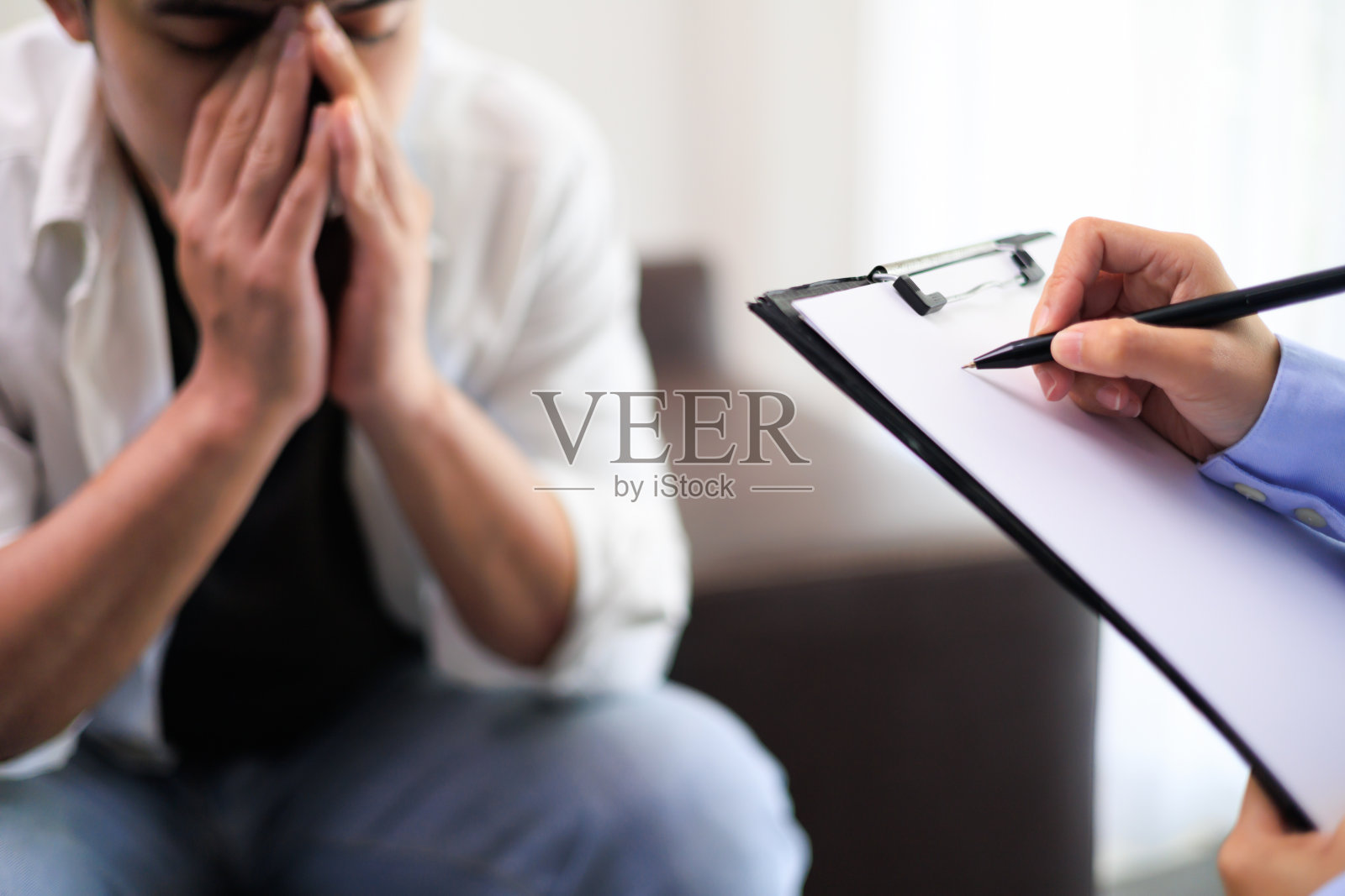 心理医生正在咨询悲伤的男人，他们感到疲倦和担心患有抑郁症。精神科医生进行谈话疗法缓解精神压力。心理健康概念。抑郁症概念。照片摄影图片