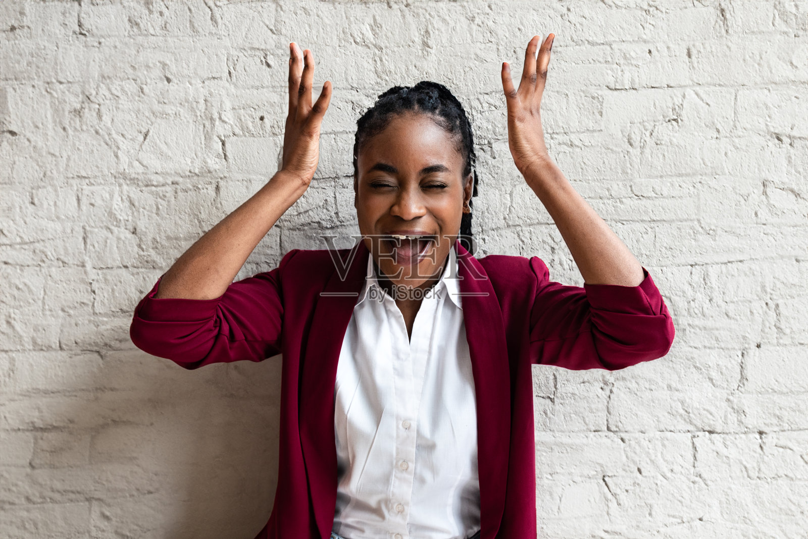 特写非裔美国人微笑着做鬼脸的年轻女商人穿着夹克看着镜头，背景是灰色的墙与复制空间。成功商务人士正装肖像照片摄影图片