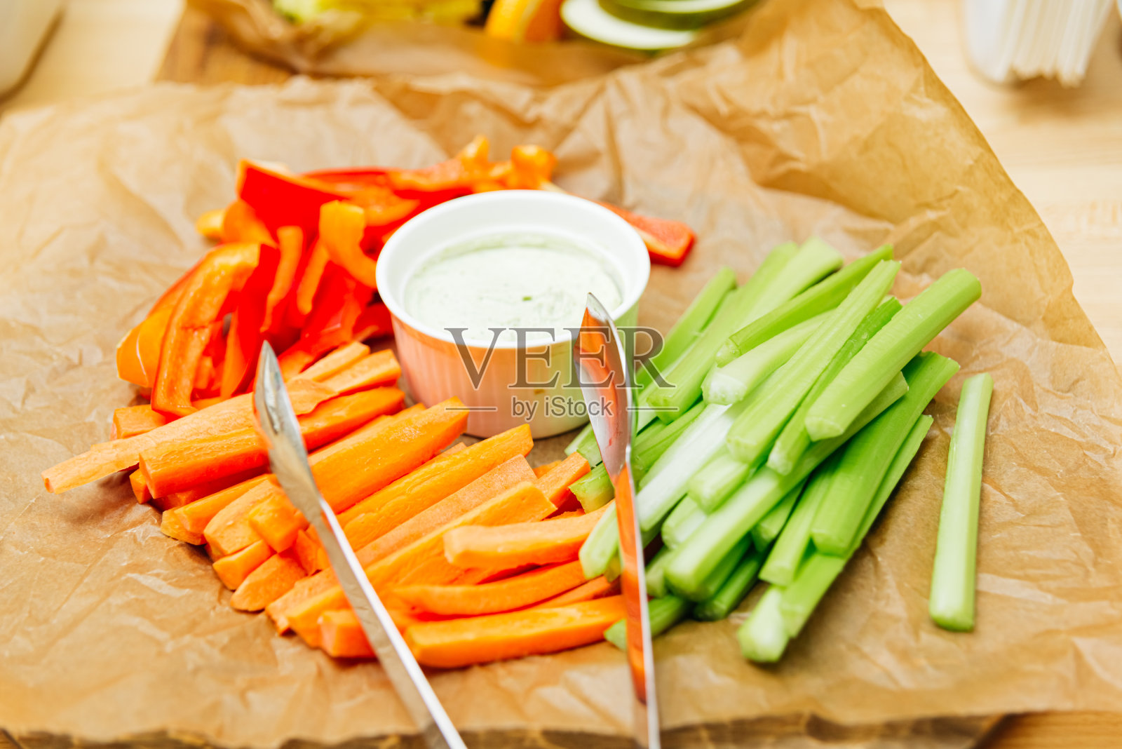 一个木制的砧板，上面放着胡萝卜和芹菜，纸上涂着酱汁照片摄影图片