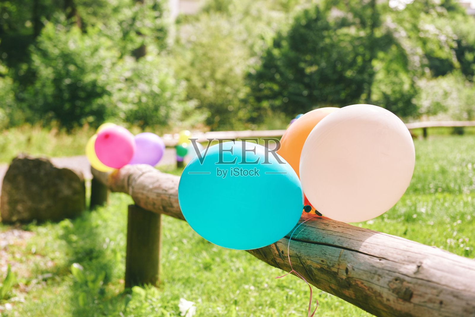 许多五颜六色的气球附着在木栅栏上，户外派对的概念照片摄影图片