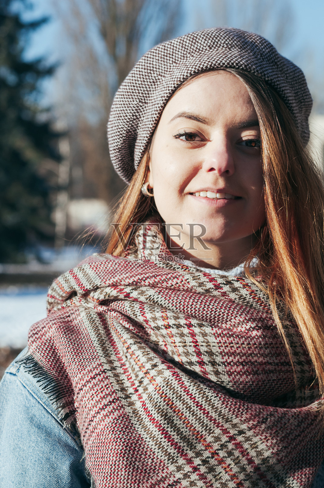 一个美丽的微笑的女孩在冬天的衣服，街头风格的肖像照片摄影图片
