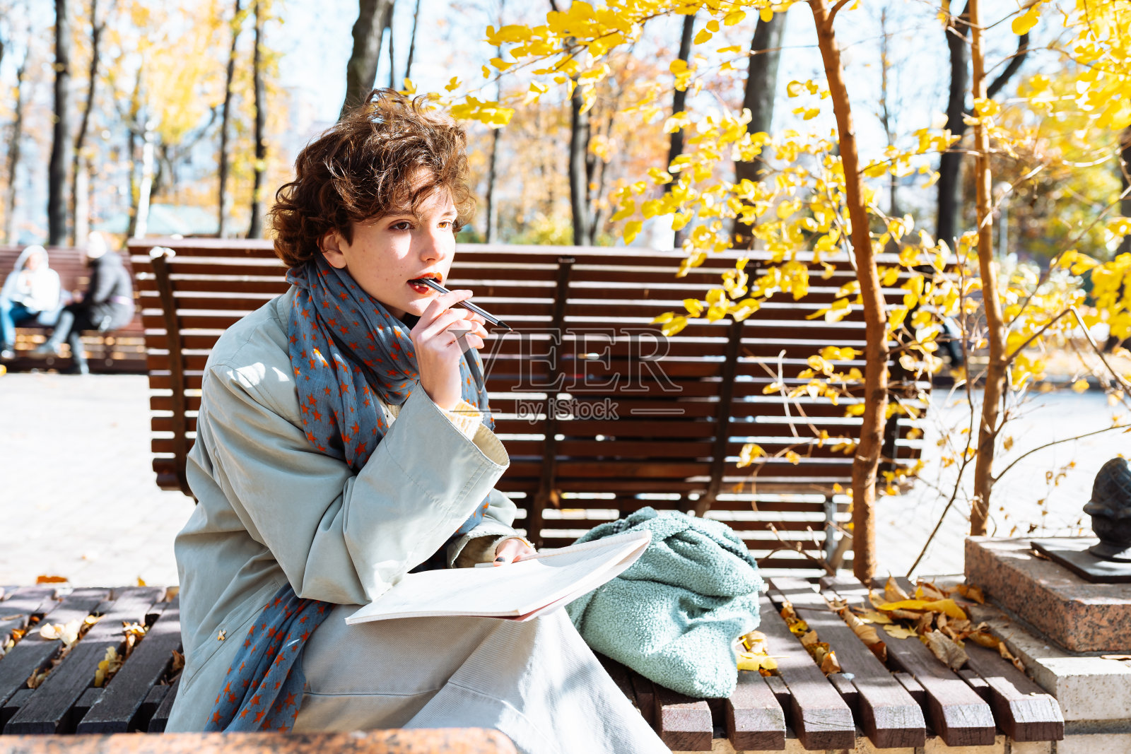 秋天的公园里，一个十几岁的学生手里拿着笔记本照片摄影图片