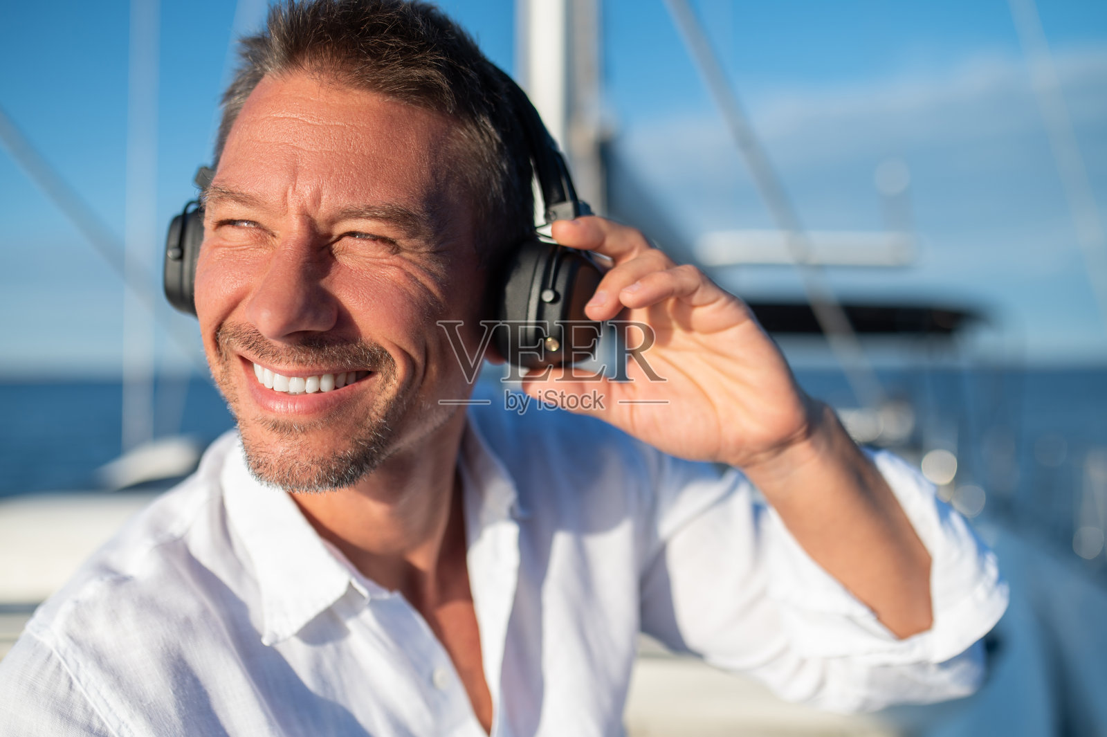 在游艇上航行时，戴着耳机听音乐的快乐男人照片摄影图片