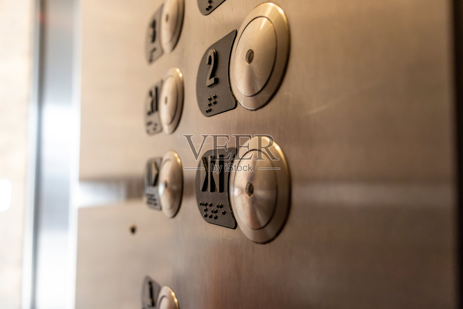 电梯控制面板的特写——不锈钢圆形按钮——数字和盲文——紧急呼叫和开门按钮照片摄影图片