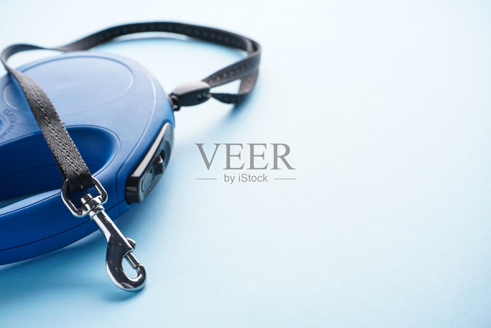 蓝色背景上的蓝色可伸缩狗绳，留出文字空间。特写镜头。照片摄影图片