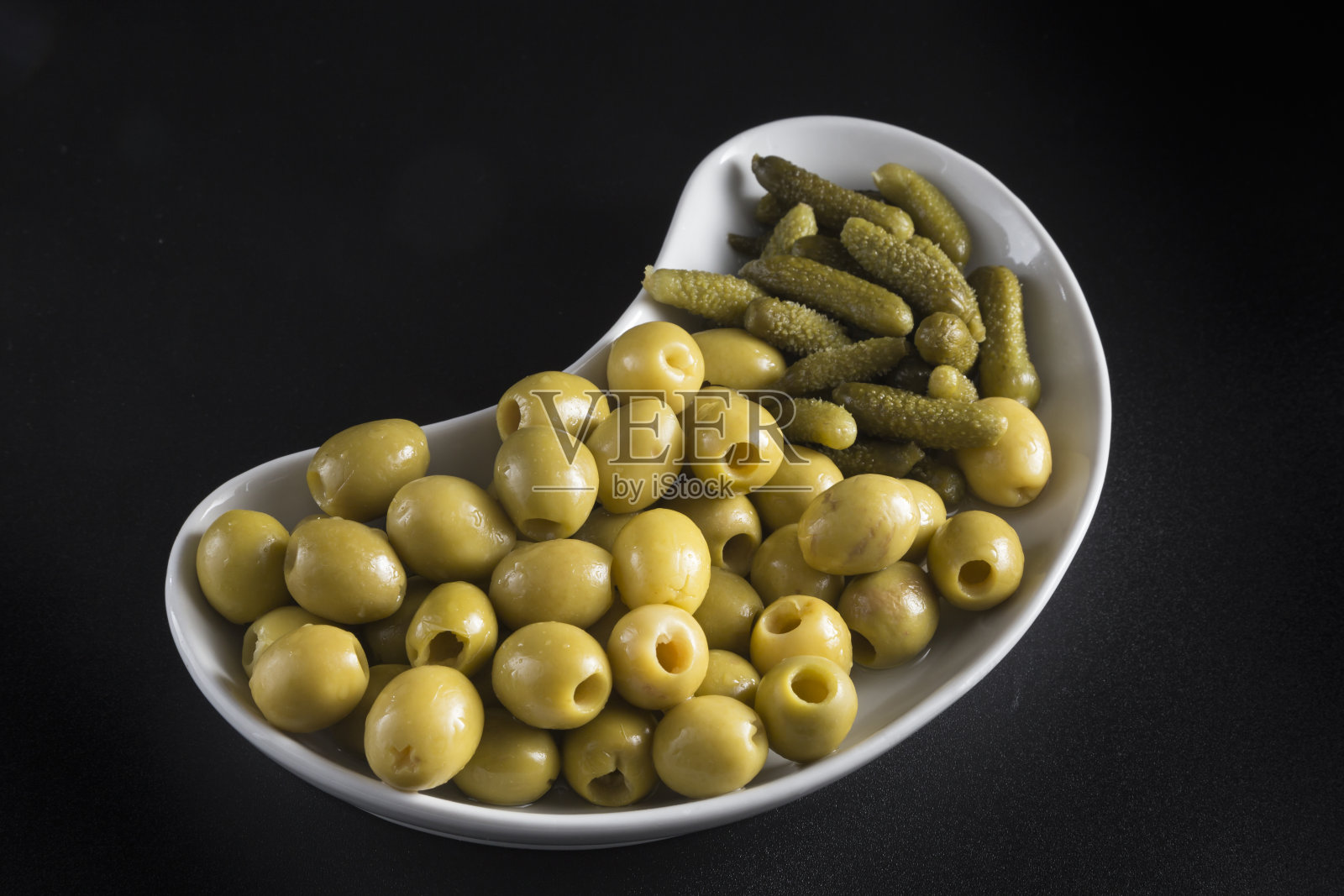 肾形托盘，上面放着咸菜和橄榄，黑色背景照片摄影图片